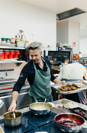 Koch Vitus Winkler beim Kochen an einem großen Herd