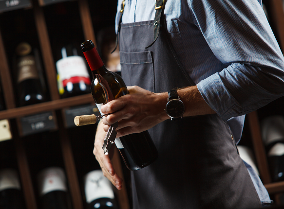 Ein Sommelier mit einer Flasche Rotwein in den Händen