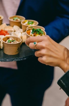 Eine Person nimmt sich ein kleines Schälchen mit Snacks