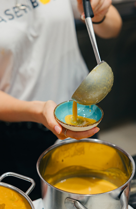 Ein Person füllt einen Schöpfer Suppe in einen Teller