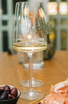 Ein Glas mit Weißwein und Antipasti auf einem Tisch