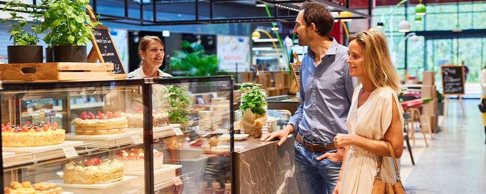 Ein Mann und eine Frau bestellen sich etwas an der Theke eines Café Cappuccino