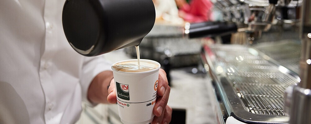 Ein Mann schenkt Kaffee in einen INTERSPAR-To-Go-Becher