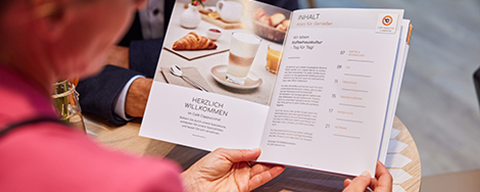 Eine Frau hält eine Speisekarte eines Café Cappuccino in den Händen