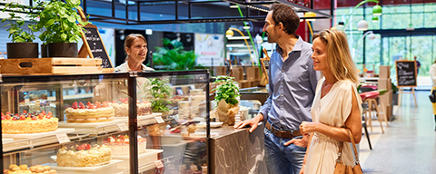 Ein Mann und eine Frau bestellen sich etwas an der Theke eines Café Cappuccino