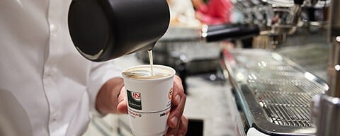 Ein Mann schenkt Kaffee in einen INTERSPAR-To-Go-Becher