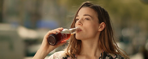 Eine Frau trinkt aus einer Glasflasche SPAR Bio Cola