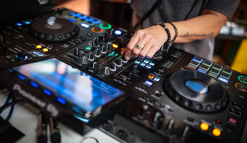 Hände einer Person, die ein DJ-Mischpult bedient