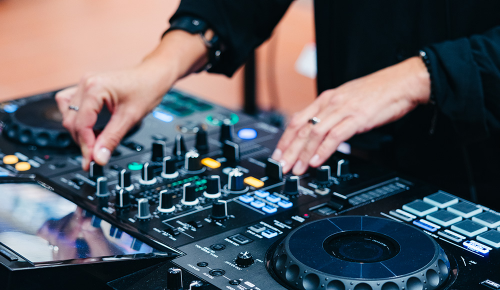 Hände einer Person, die ein DJ-Mischpult bedient