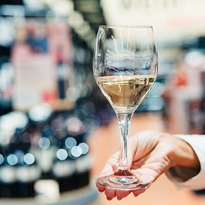Eine Person hält ein Glas mit Weißwein in der Hand