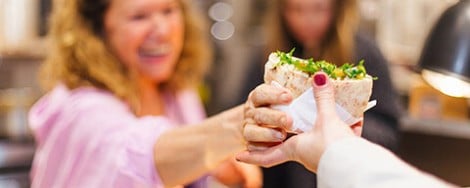 Eine Frau bekommt einen frischen Wrap gereicht