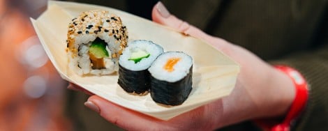 Eine Person hält eine Schale mit Sushi in der Hand