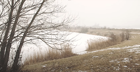 Zwei Personen stehen neben einem Feld im Winter und unterhalten sich