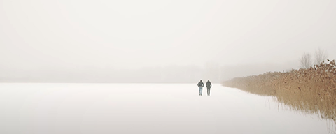 Zwei Personen gehen an einem Feld im Winter vorbei