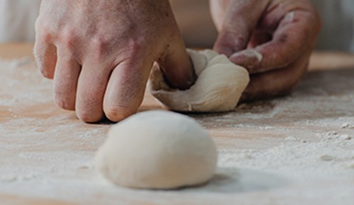 Hände eines Bäckers beim Formen von Brötchen