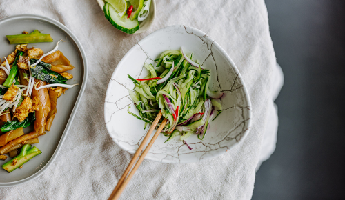 Thailändischer Gurkensalat in einem weißen Suppenteller mit Esstäbchen