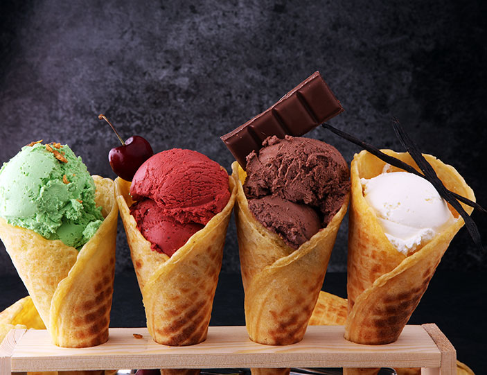 4 Kugeln Eis in jeweils einer Waffel mit Kirsche, Schokolade und Vanille garniert