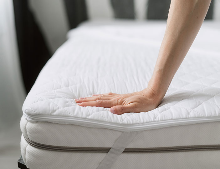 Person erfühlt mit der Hand die Matratzenstärke