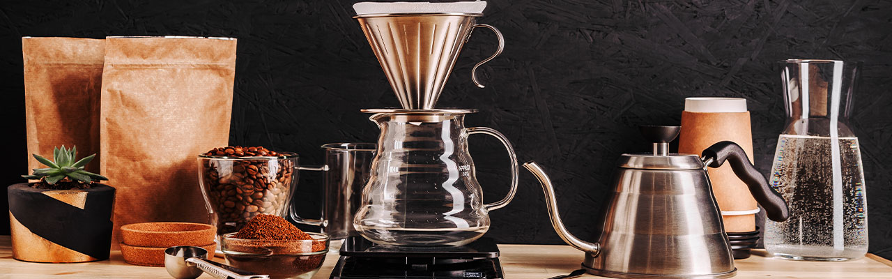Filterkaffeemaschine mit gemahlenem Kaffee und Kaffeebohnen in Glasschüsselchen daneben