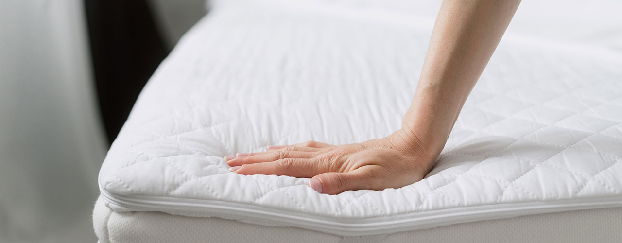 Person erfühlt mit der Hand die Matratzenstärke