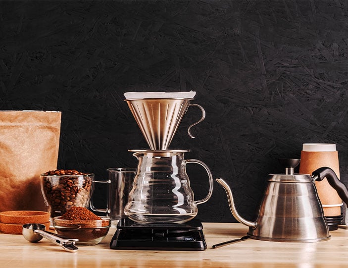 Filterkaffeemaschine mit gemahlenem Kaffee und Kaffeebohnen in Glasschüsselchen daneben