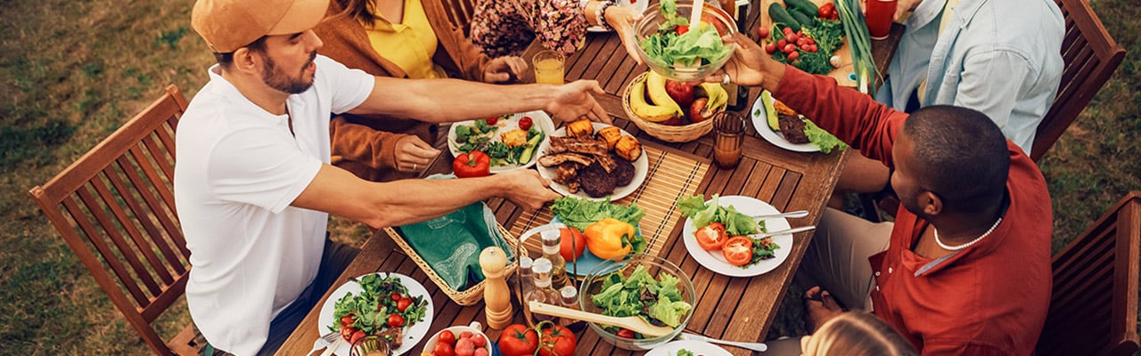 Leute sitzen im Garten an einem großen Tisch und essen